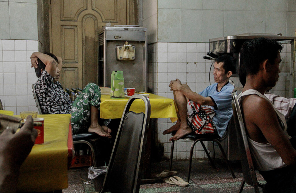 San Pyout and his wife wait for their son at a tea shop. The tea shop is the family’s regular gathering place for breakfast, as San Pyout’s two sons live in his brother’s house.