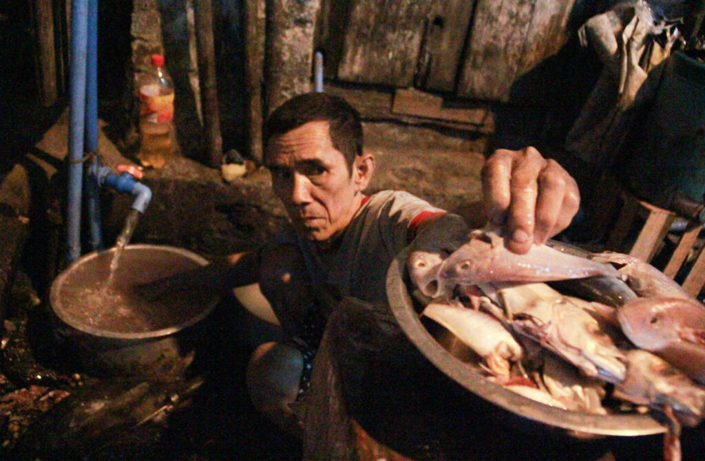 San Pyout, 56, prepares fish to cook for the customers.