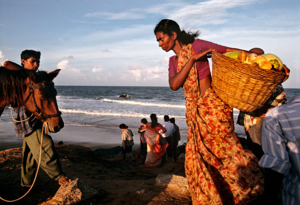 INDIA. Women carrying raw coconuts, Kanyakumari Beach 1995