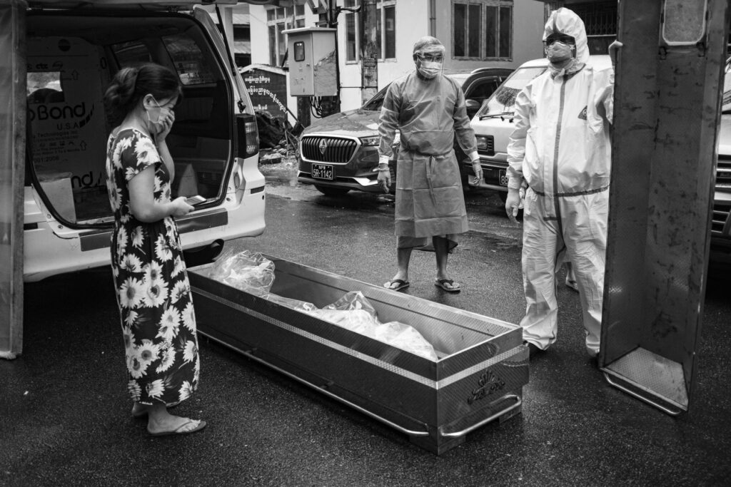 Sister of the deceased woman who died of Covid-19 symptons mourns as free funeral service volunteer arrives to pick up the body to send to cemetery in Yangon on 20 July 2021.