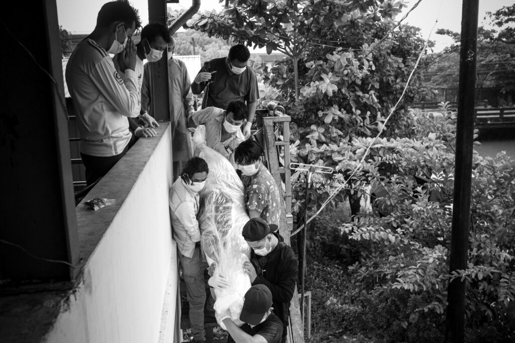 Volunteers carrying a body of deceased woman who died of with Covid-19 symptons at a factory's domitory on the outskirts of Yangon on 22 July 2021.