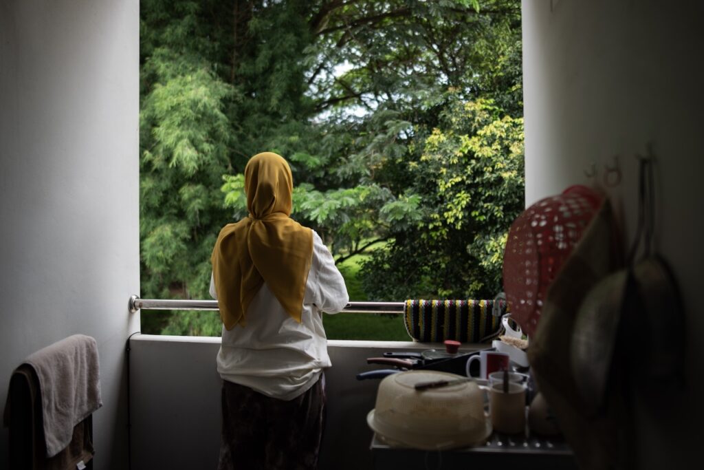 Myanmar migrant Pyar Tho looks out from her apartment in Chiang Mai after fleeing conflict in Myanmar. Now settled in northern Thailand, she is among thousands seeking safety and a chance to rebuild their lives, as many displaced people carry lasting psychological scars including grief, fear and the trauma of displacement.