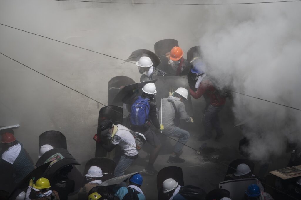 Tear gas and fire extinguisher gas float around protesters as they take shelter behind shields while clashing with riot police officers during a protest against the military coup in Yangon, Myanmar, March 1, 2021.